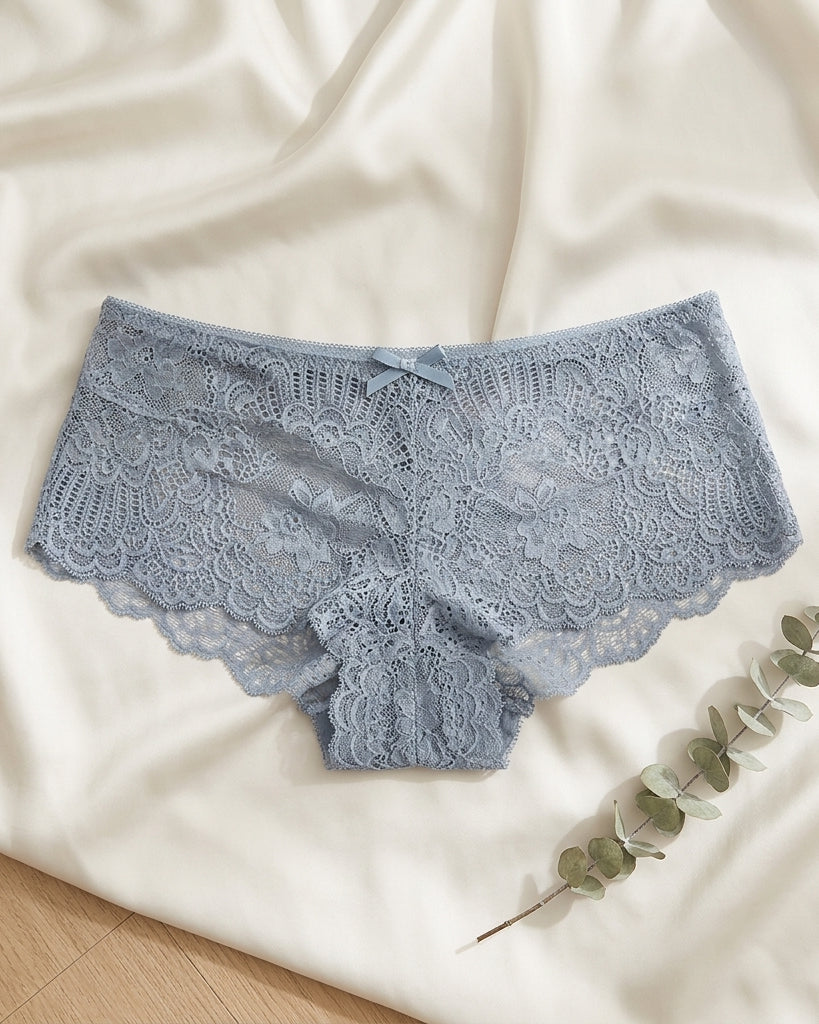 Blue lace underwear on a white fabric background with a branch of eucalyptus.