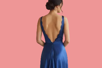Woman wearing a blue evening gown with an open back against a beige background