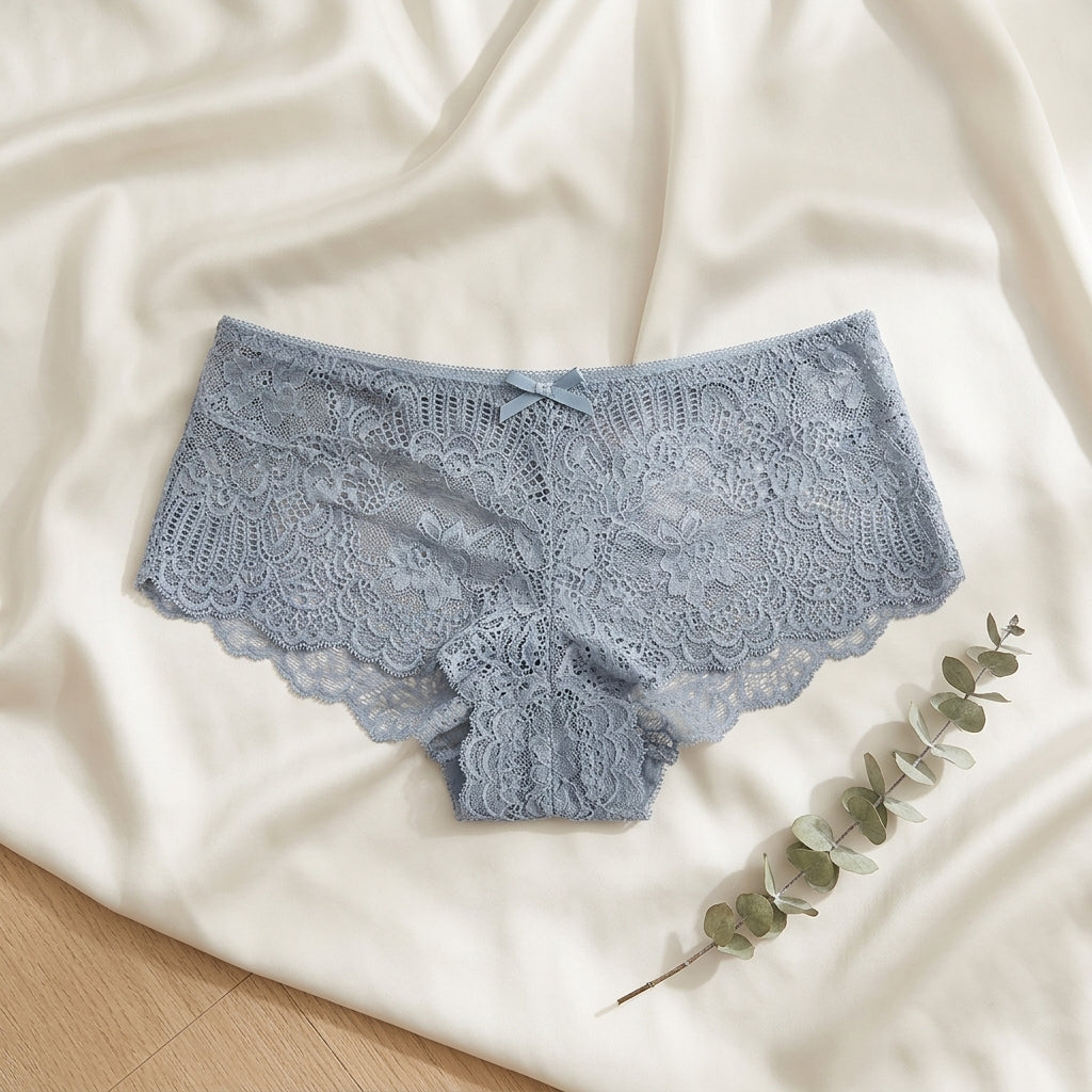 Blue lace underwear on a white fabric background with a branch of eucalyptus.